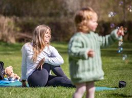 A child blows bubbles during a yoga class outside