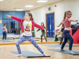 A child performing a warrior yoga pose