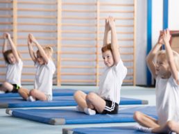 Preschool children doing back stretches on a mat