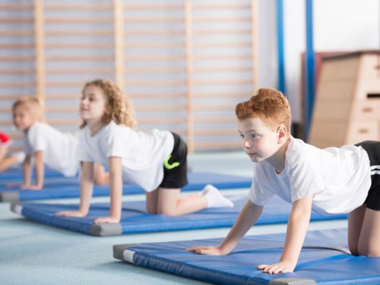 School children performing the cow yoga pose