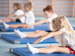 Children doing a lower back stretch on the floor