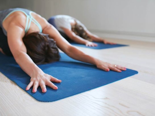 Two women practicing the extended puppy yoga pose